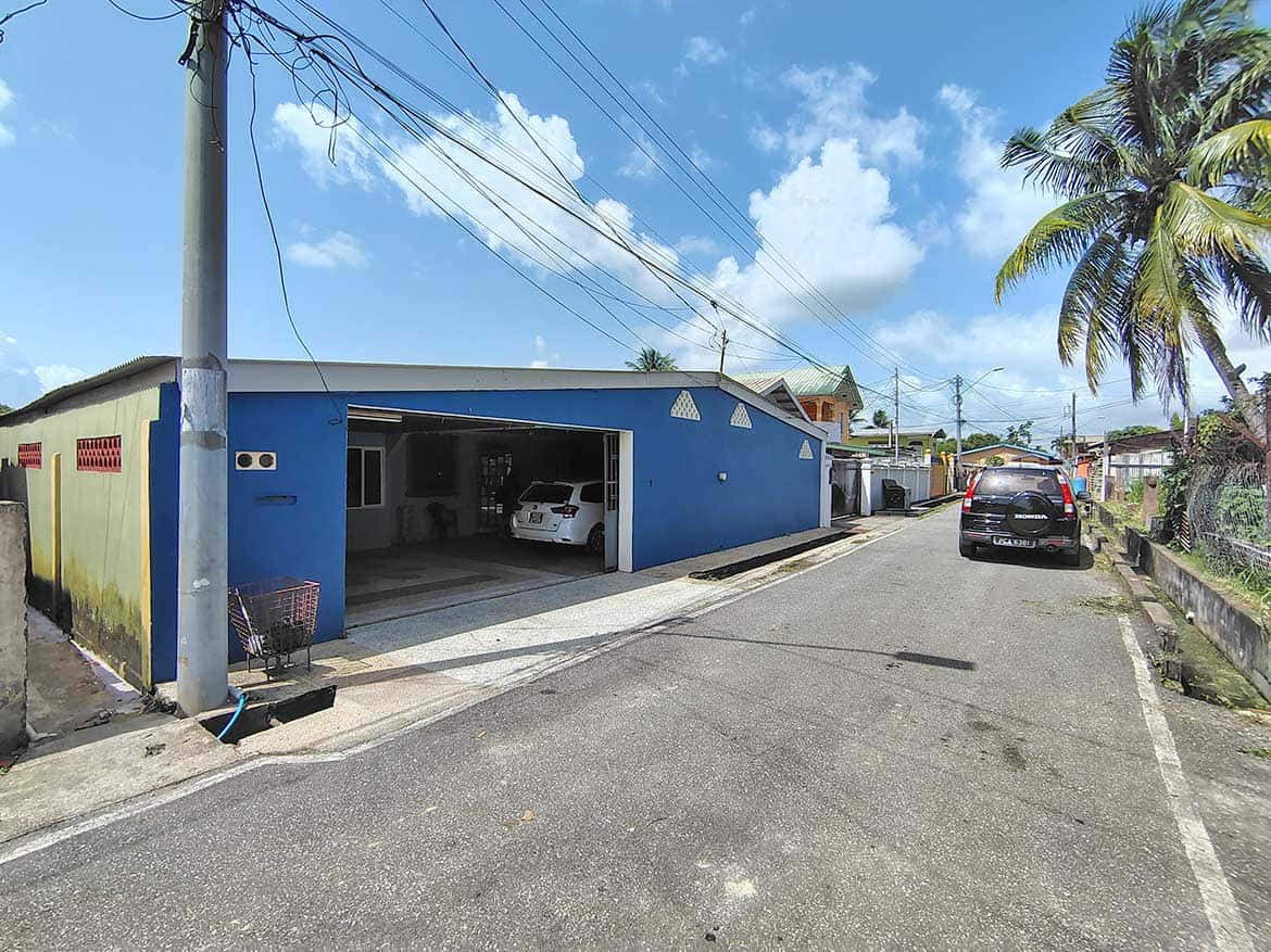 Blue residential building with garage and parked cars on a sunny day.