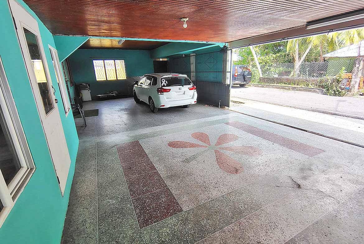 Covered parking space with a white car and decorative floor design.