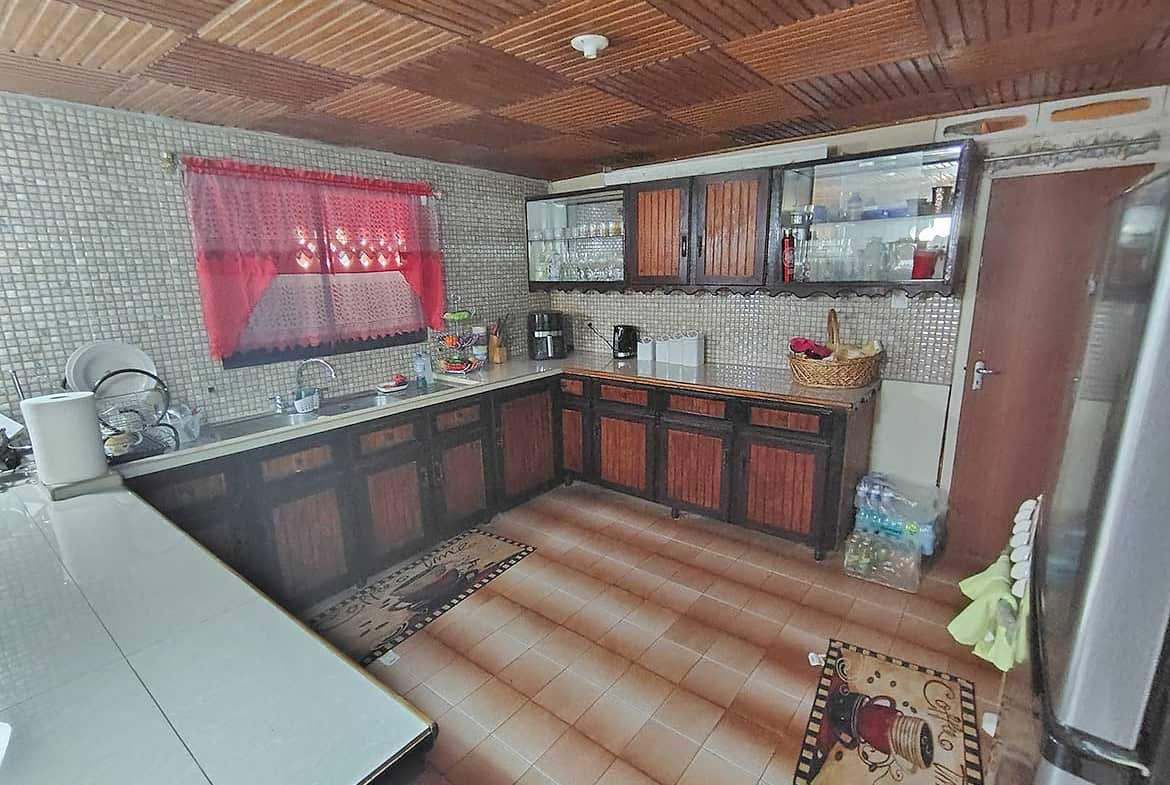 Cozy kitchen with wooden cabinets, tiled walls, and a red curtain window.