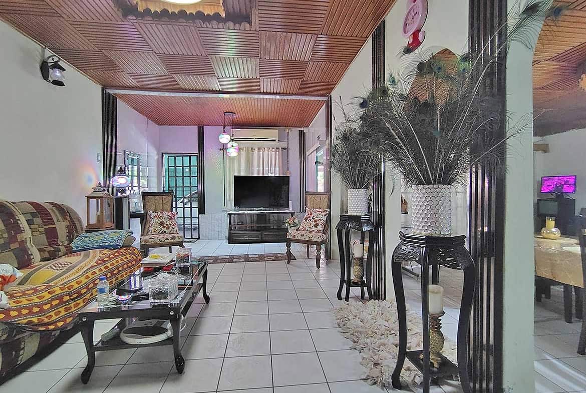 Spacious living room with wooden ceiling, large TV, and decorative plants.