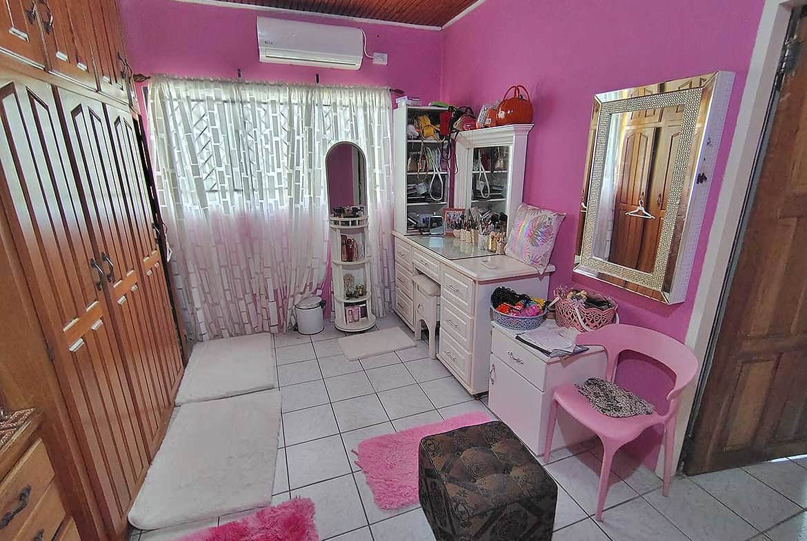 Cozy bedroom with pink walls, white furniture, and decorative accents.