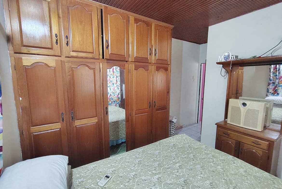 Bedroom with large wooden wardrobe and bed with green bedspread.