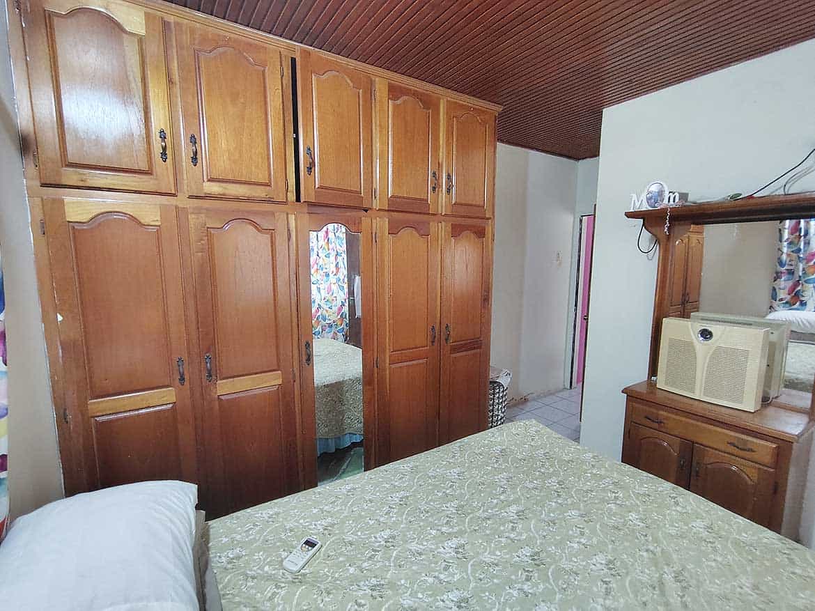 Cornerstone™ Bedroom with Wooden Wardrobe Bedroom with large wooden wardrobe and bed with green bedspread.