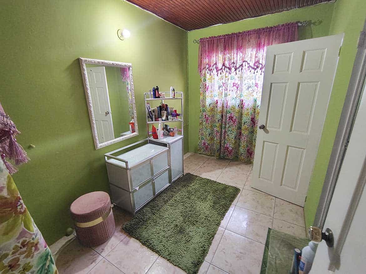 Cornerstone™ Interior of Bedroom Bright bedroom with green walls, floral curtains, and a mirror.