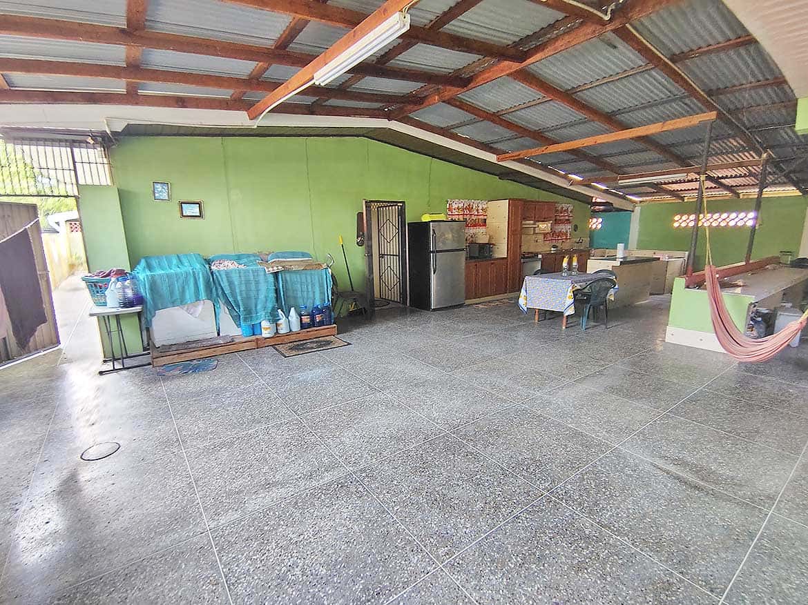 Spacious Covered Outdoor Area at Alexander Street Large open outdoor space with green walls, tables, and a hammock under a metal roof.