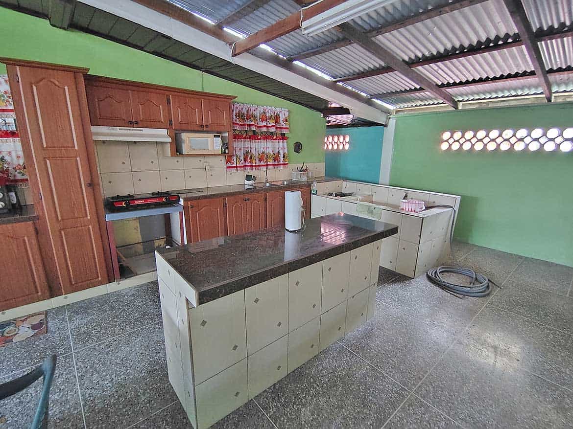 Cornerstone™ Kitchen with Green Walls Spacious kitchen with green walls, wooden cabinets, and a central island.