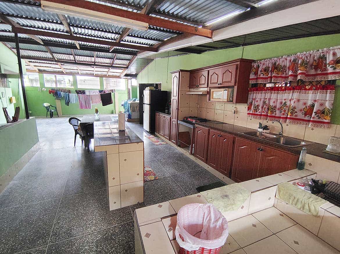 Cornerstone™ Alexander Street Kitchen Spacious kitchen with green walls, wooden cabinets, and laundry area in the background.