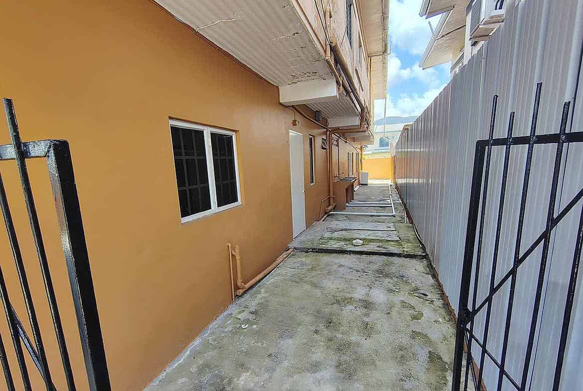 Cornerstone- Narrow outdoor corridor between building and fence at Cornerstone™ EMR Tacarigua Apt 4.