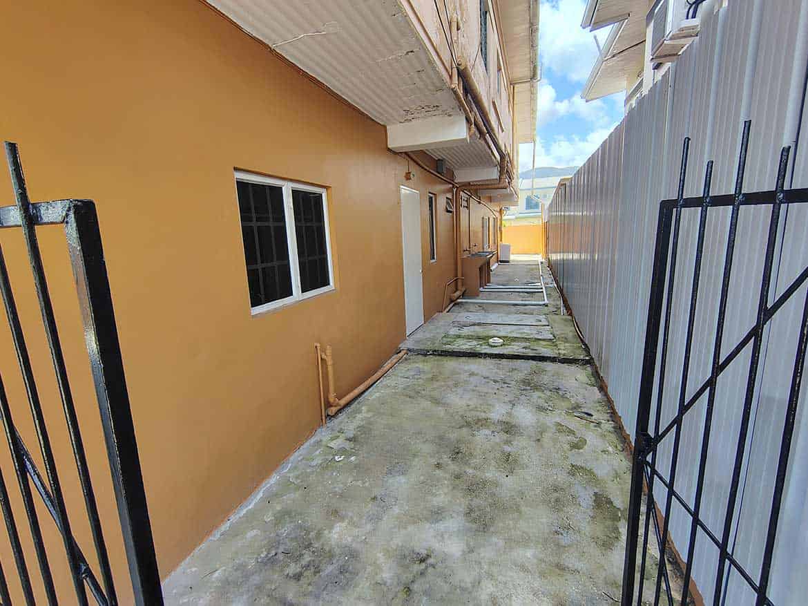 Cornerstone™ EMR Tacarigua Apt 4 Cornerstone- Narrow outdoor corridor between building and fence at Cornerstone™ EMR Tacarigua Apt 4.