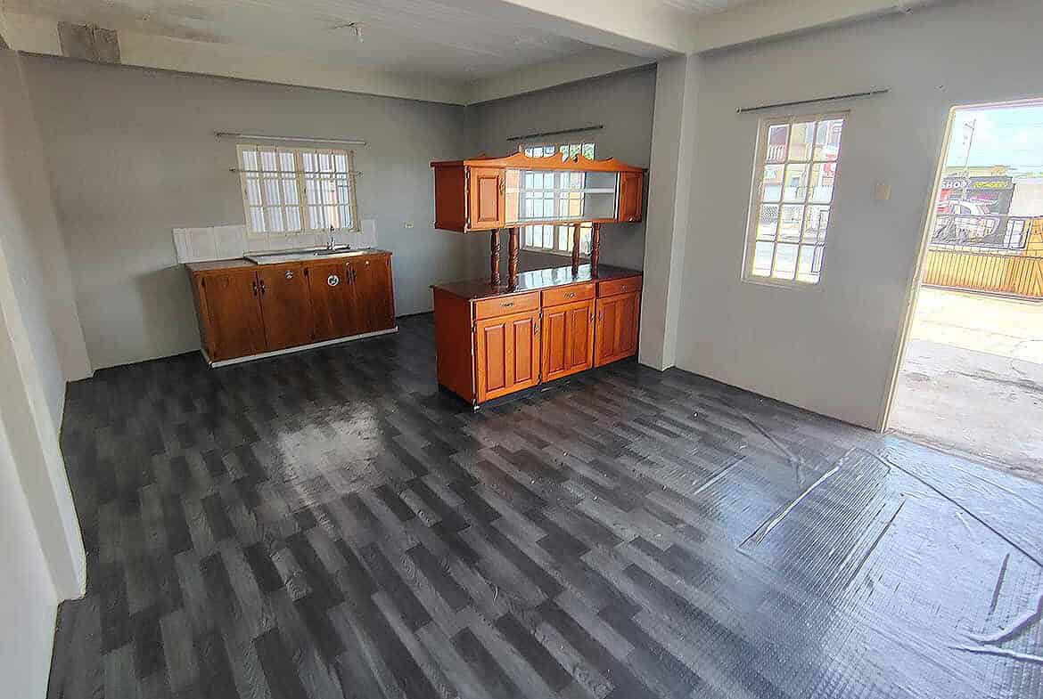 Cornerstone- Spacious living area in Cornerstone™ EMR Tacarigua apartment with wooden cabinets and large windows.