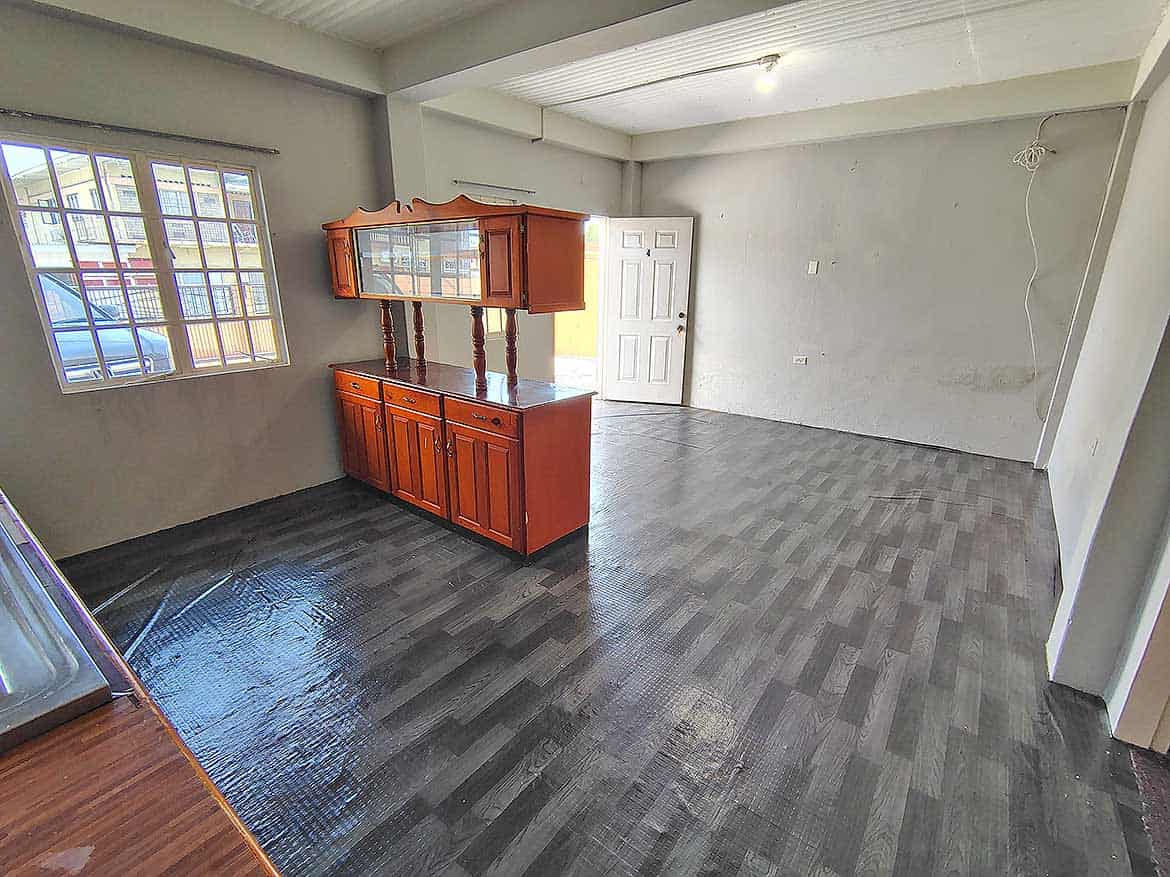 Interior of EMR Tacarigua Apt 4 Cornerstone- Spacious living room with dark flooring and large window in EMR Tacarigua Apt 4.