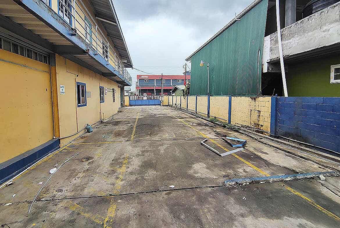 Cornerstone- Vacant parking lot with yellow lines and surrounding buildings in Trinidad.