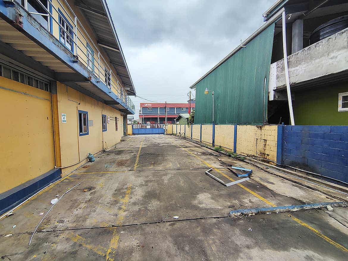 Empty Parking Lot Near Cornerstone Cornerstone- Vacant parking lot with yellow lines and surrounding buildings in Trinidad.