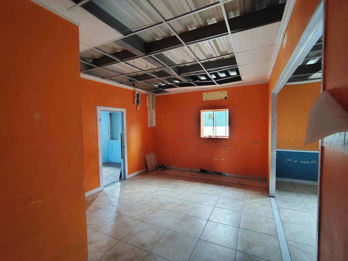 Interior of Cornerstone™ Office Space Cornerstone- Empty office room with orange walls and open ceiling panels.