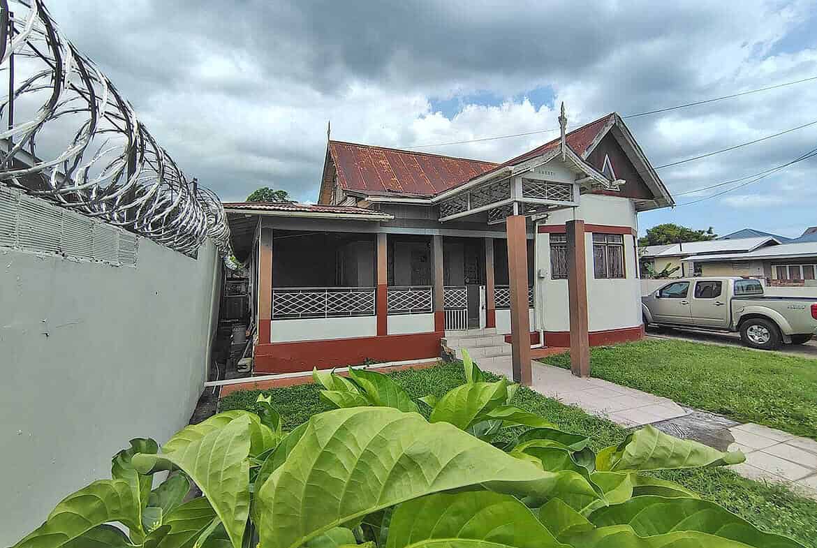 Cornerstone- Residential house on Carlos Street, Woodbrook with garden and parked vehicle.