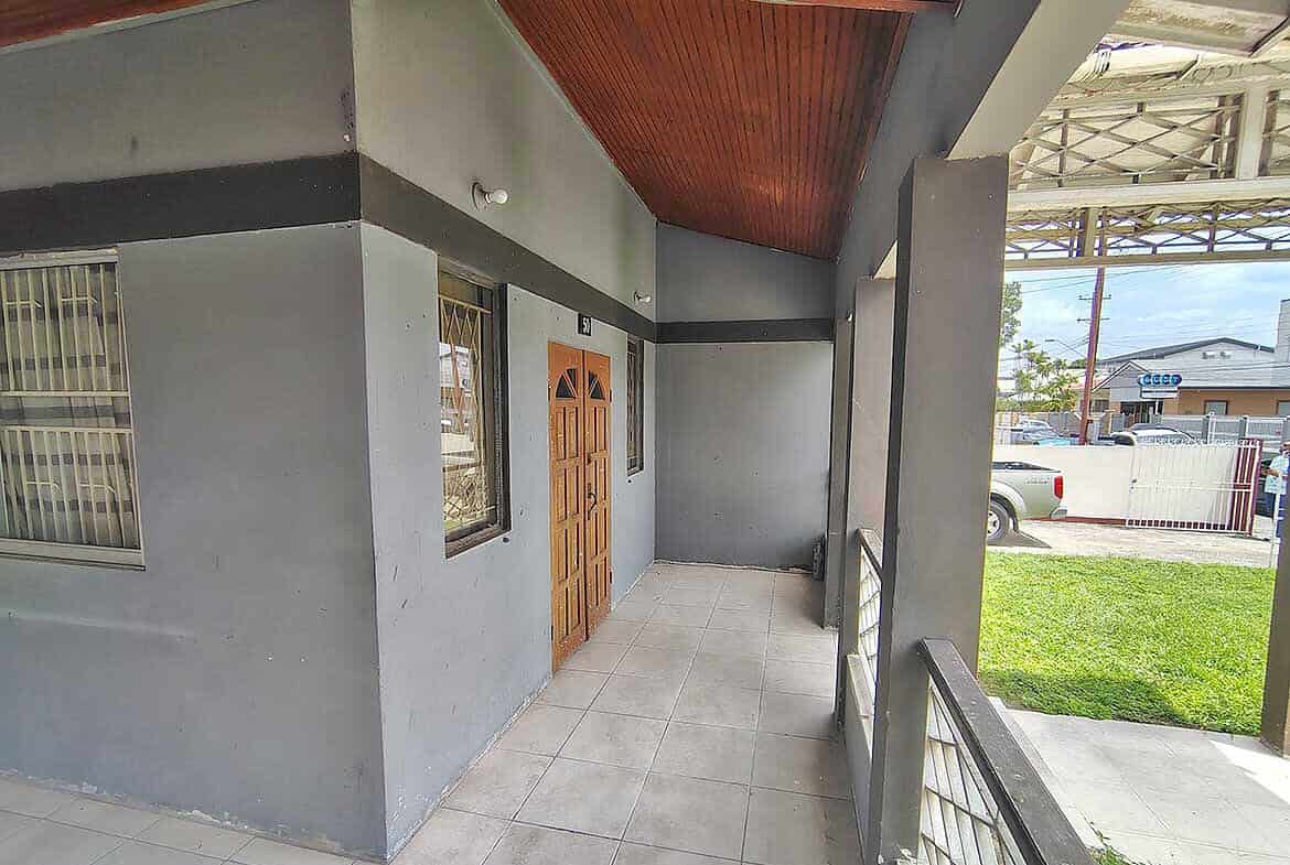 Cornerstone- Modern commercial building entrance with wooden door and tiled porch.