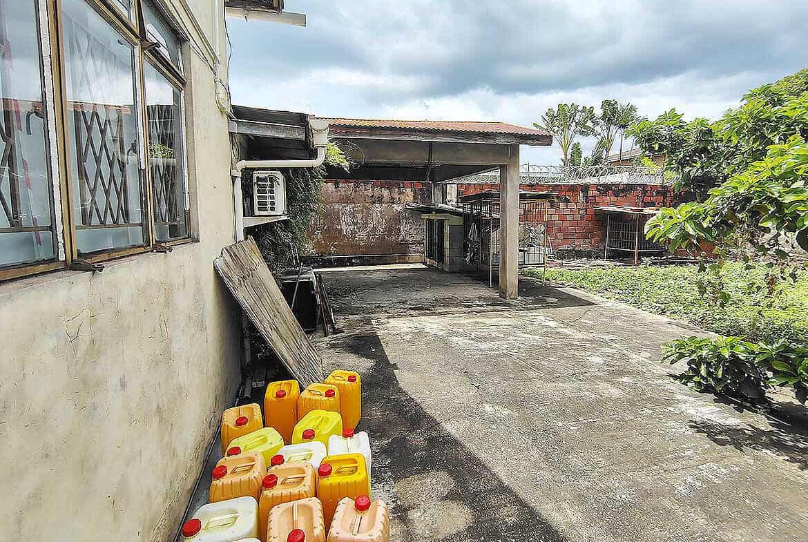 Cornerstone- Residential backyard with water containers and garden in Woodbrook, Trinidad.