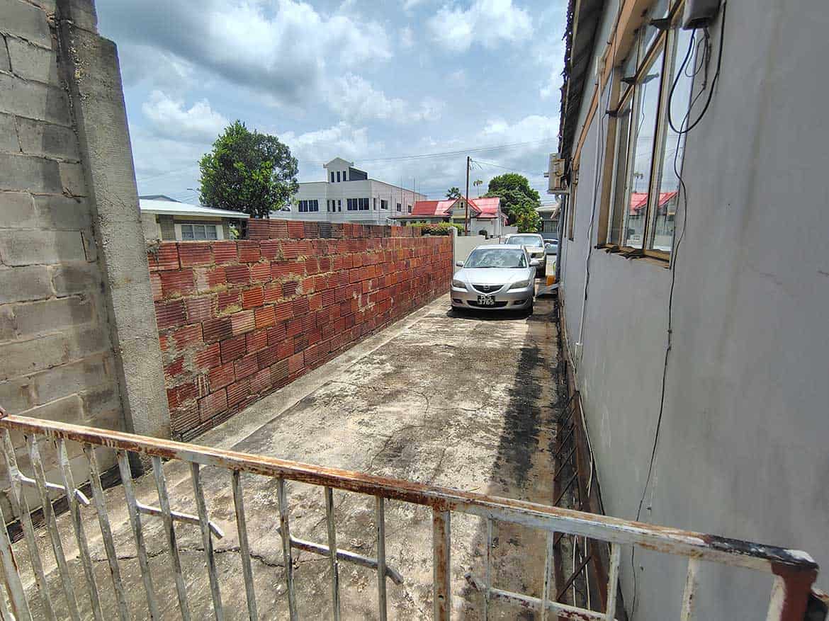 Carlos Street Woodbrook Parking Area Cornerstone- Empty parking space on Carlos Street in Woodbrook with a parked car and surrounding buildings.