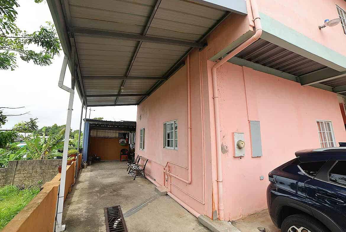 Cornerstone- Pink residential building with carport and parked vehicle in Arima.