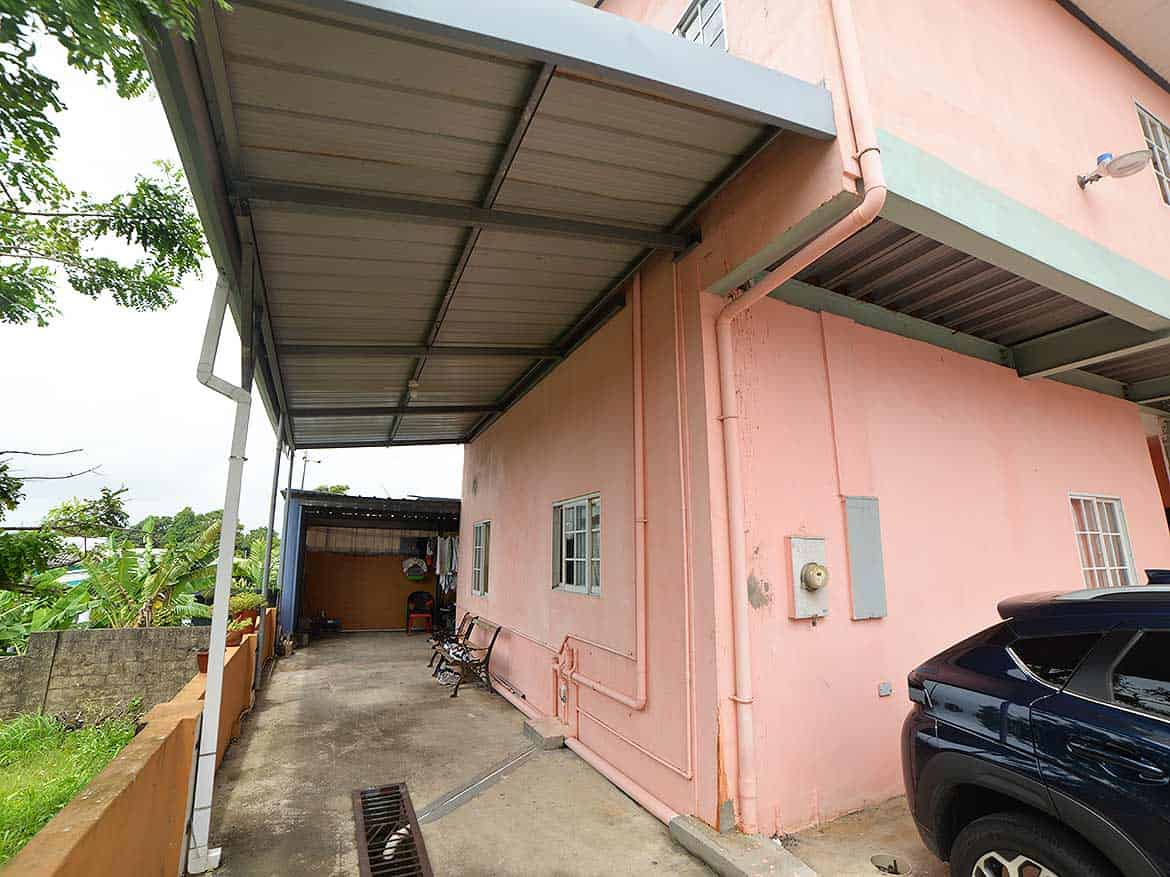 Cornerstone™ Residential Building Exterior Cornerstone- Pink residential building with carport and parked vehicle in Arima.