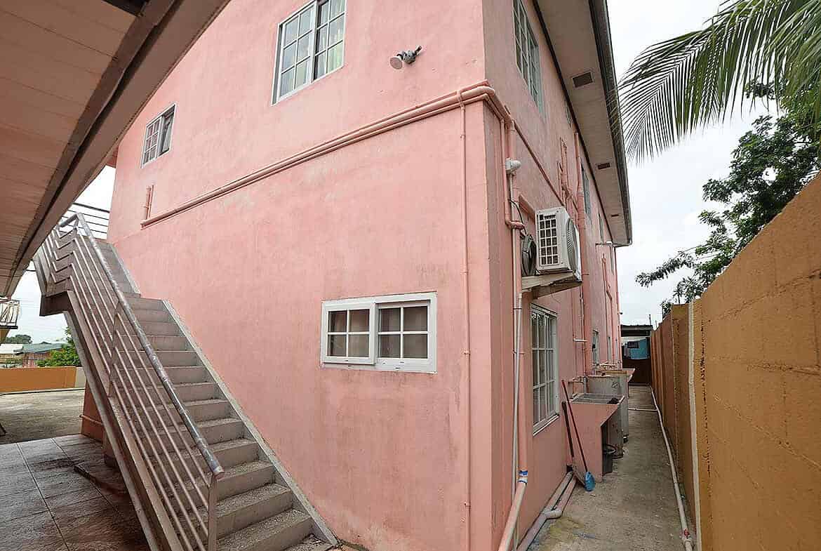 Cornerstone- Pink residential building with external stairs and air conditioning units.