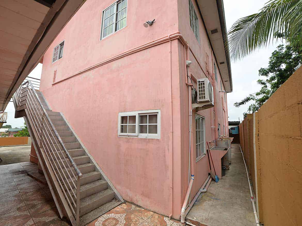 Cornerstone™ Residential Building Exterior Cornerstone- Pink residential building with external stairs and air conditioning units.