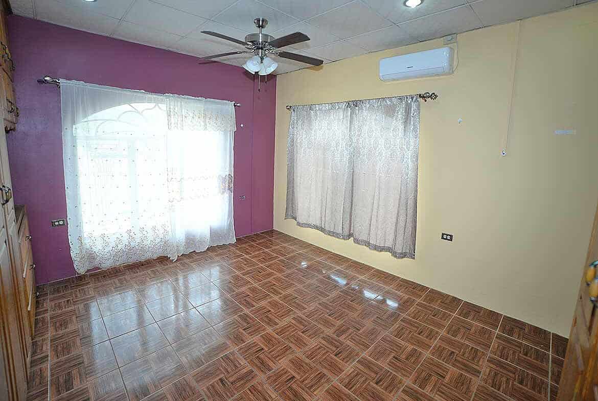 Cornerstone- Spacious room with purple and yellow walls, ceiling fan, air conditioning, and large windows with dr.