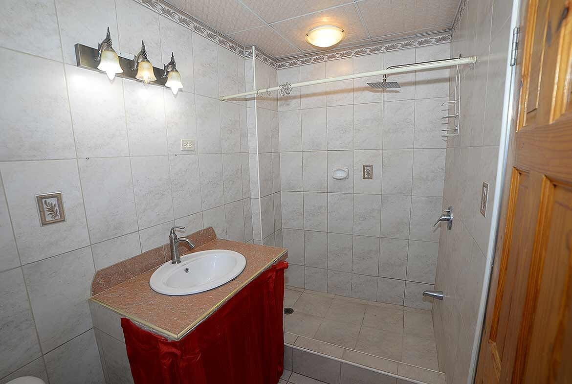 Cornerstone- Bathroom with walk-in shower, sink, and wooden door at Cleaver Road, Arima.