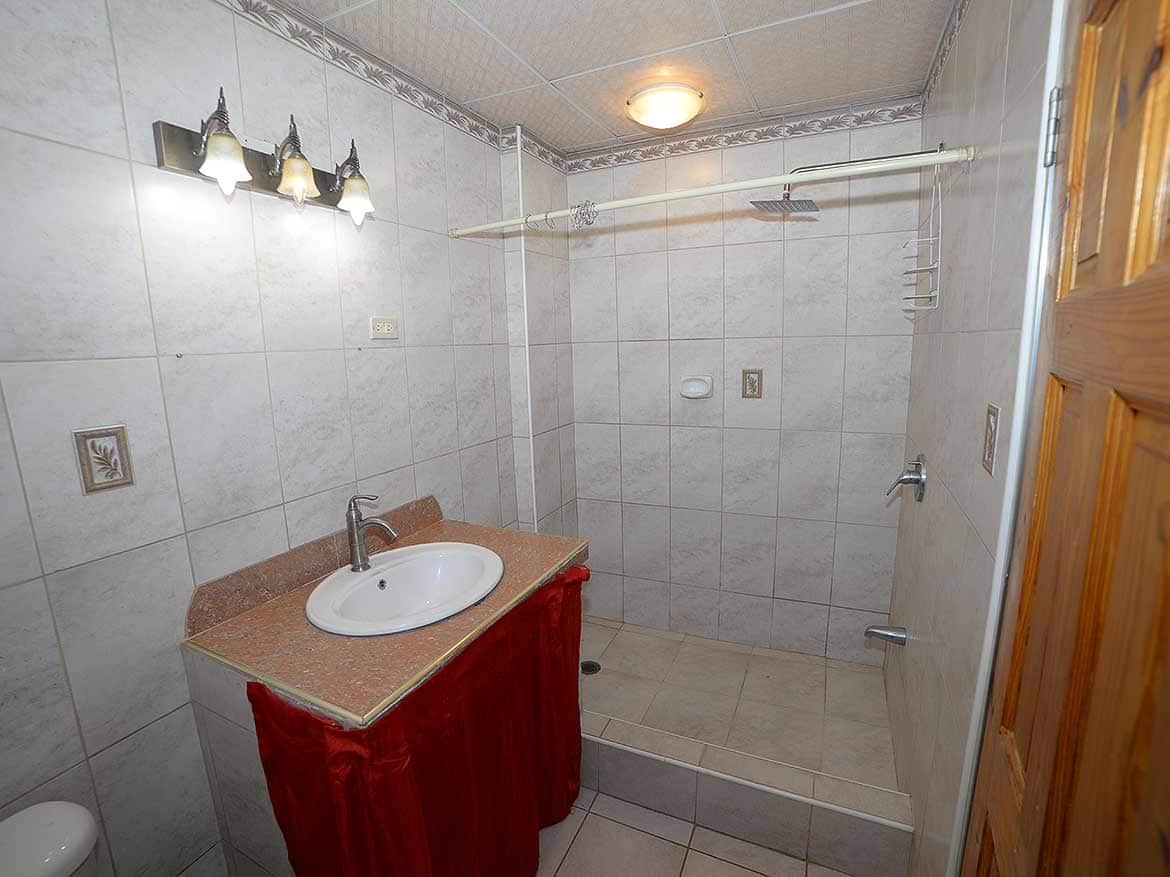 Bathroom with walk-in shower at Cleaver Road Cornerstone- Bathroom with walk-in shower, sink, and wooden door at Cleaver Road, Arima.