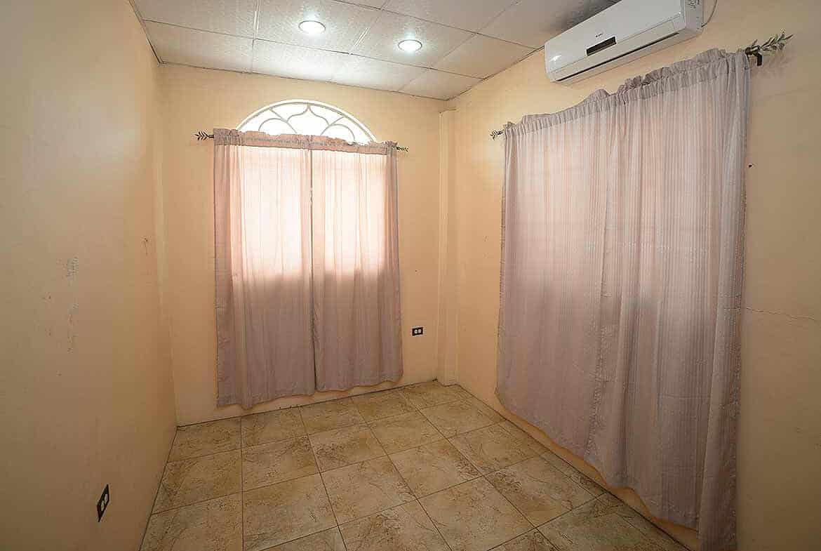 Cornerstone- Empty room with beige walls, tiled floor, and curtains on windows.