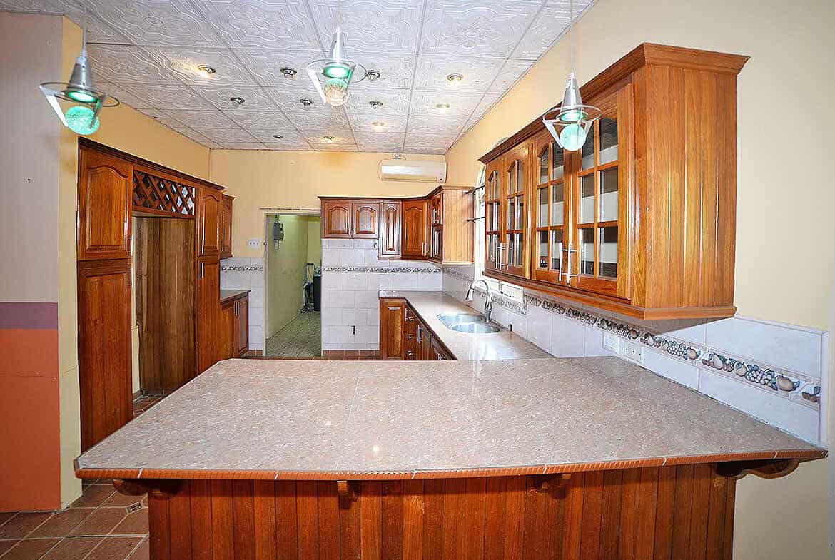 Cornerstone- Spacious kitchen with wooden cabinets and a breakfast bar in Arima.