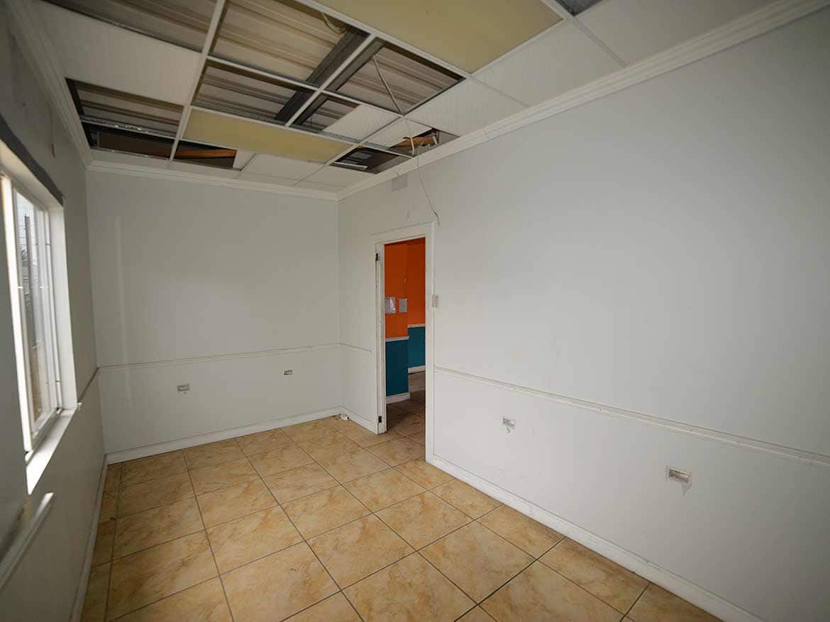 Interior of a Room Under Renovation Cornerstone- Empty room with damaged ceiling and tiled floor, under renovation.