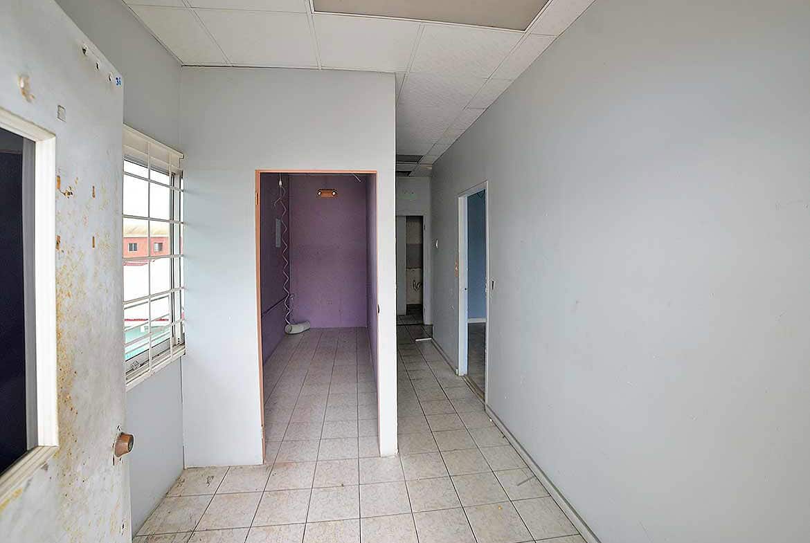 Cornerstone- Empty corridor inside a commercial building with windows and doorways.