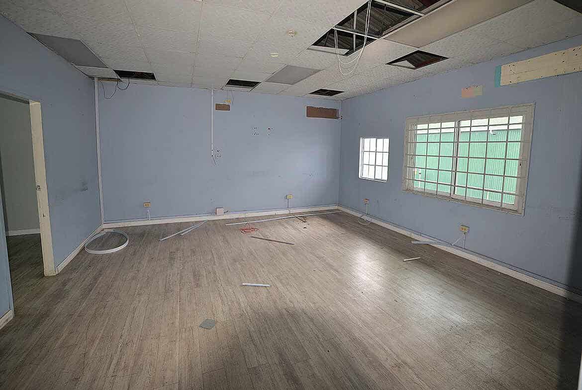 Cornerstone- Empty office room with damaged ceiling and light blue walls.