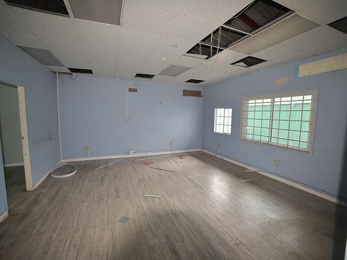 Interior of a vacant office space Cornerstone- Empty office room with damaged ceiling and light blue walls.