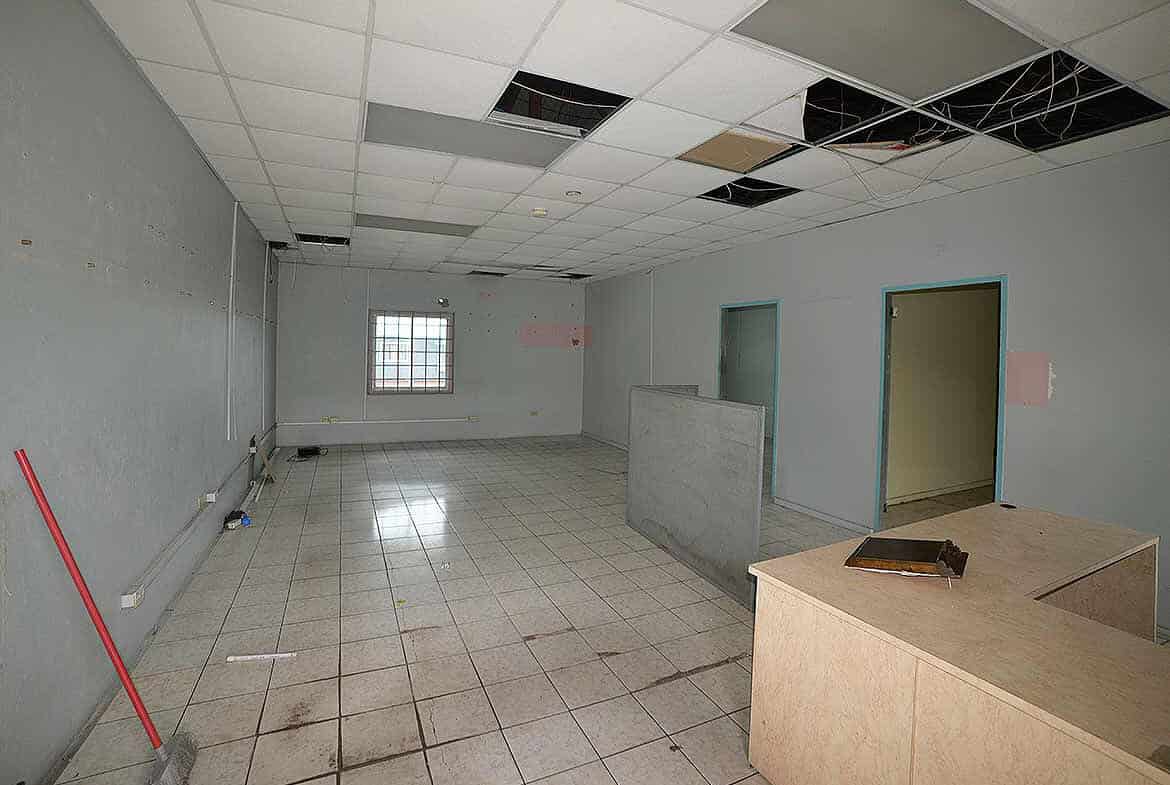 Cornerstone- Empty commercial space with ceiling tiles missing and construction materials.