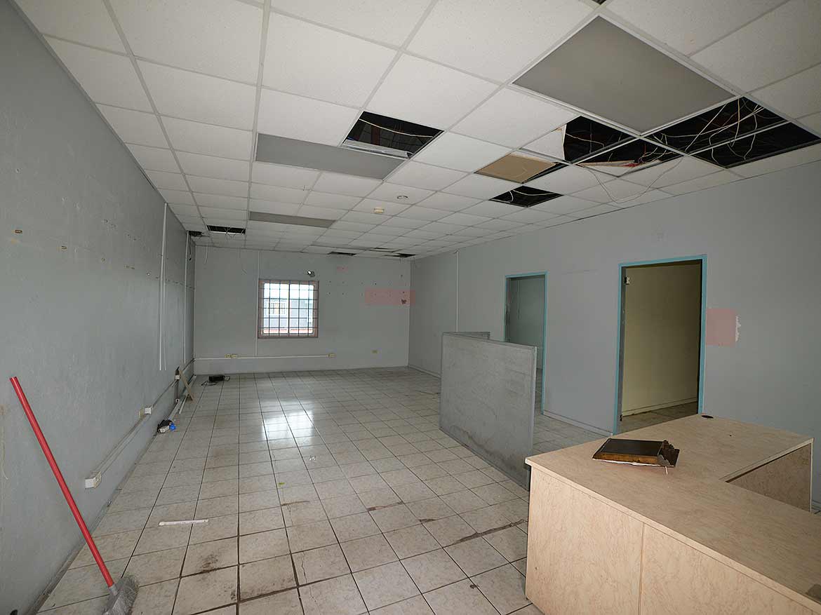 Interior of Commercial Space Under Renovation Cornerstone- Empty commercial space with ceiling tiles missing and construction materials.