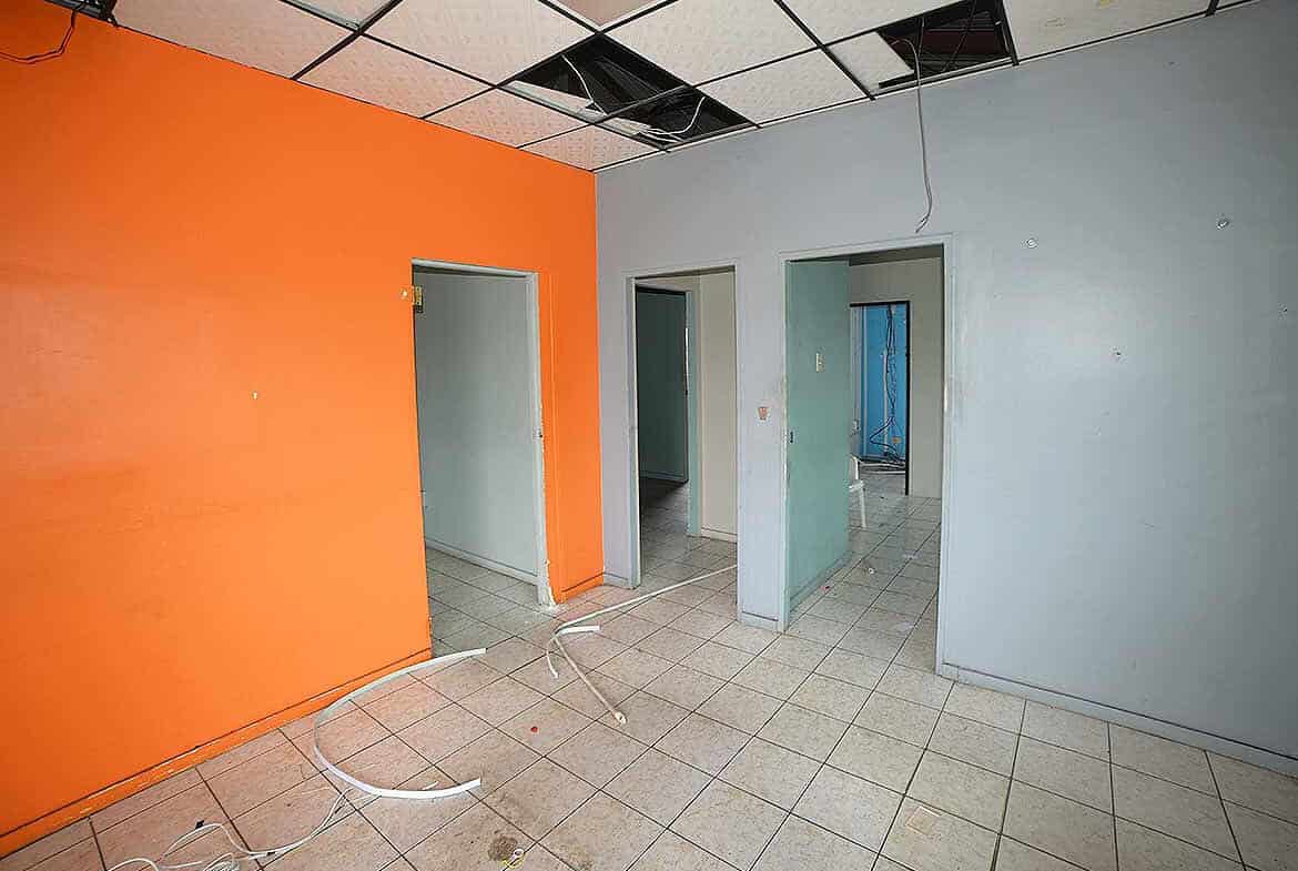 Cornerstone- Room with orange and blue walls, ceiling tiles missing, and construction wires.