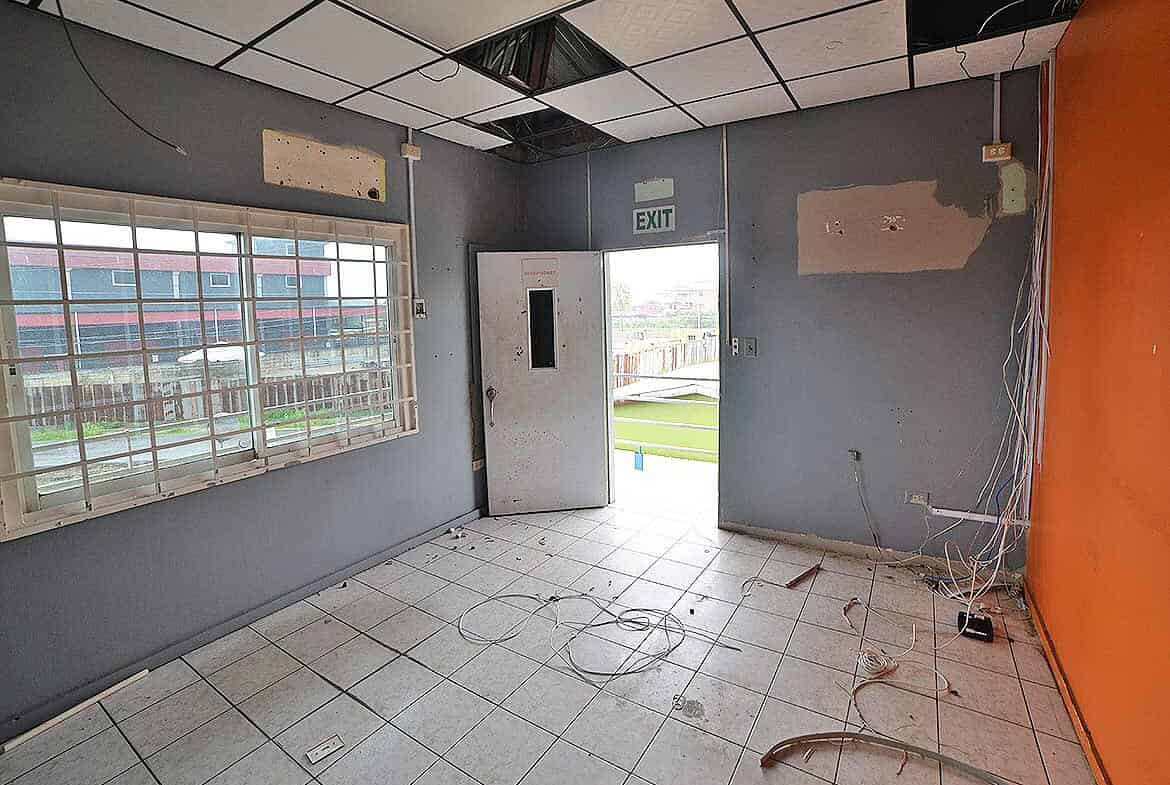 Cornerstone- Empty office room with damaged ceiling and wires on the floor.