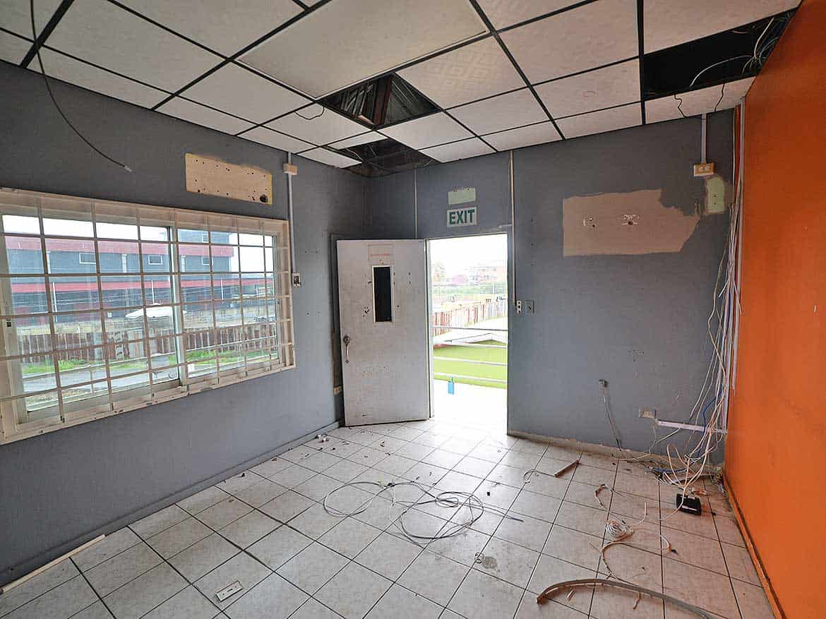 Interior of a vacant office space Cornerstone- Empty office room with damaged ceiling and wires on the floor.
