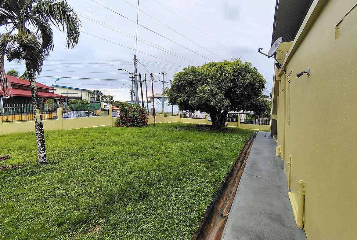Cornerstone- Lush green yard with trees and power lines in Corinth, Trinidad and Tobago.