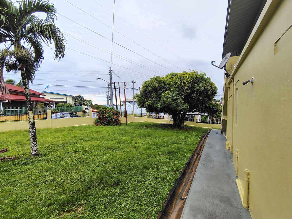 Cornerstone™ Braemar Road, Corinth Cornerstone- Lush green yard with trees and power lines in Corinth, Trinidad and Tobago.