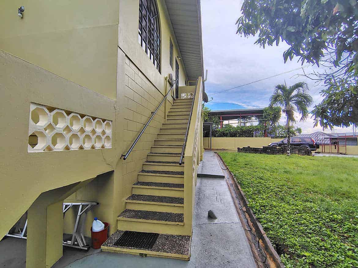 Cornerstone™ Residential Building Exterior Cornerstone- Exterior view of a yellow residential building with stairs and greenery.