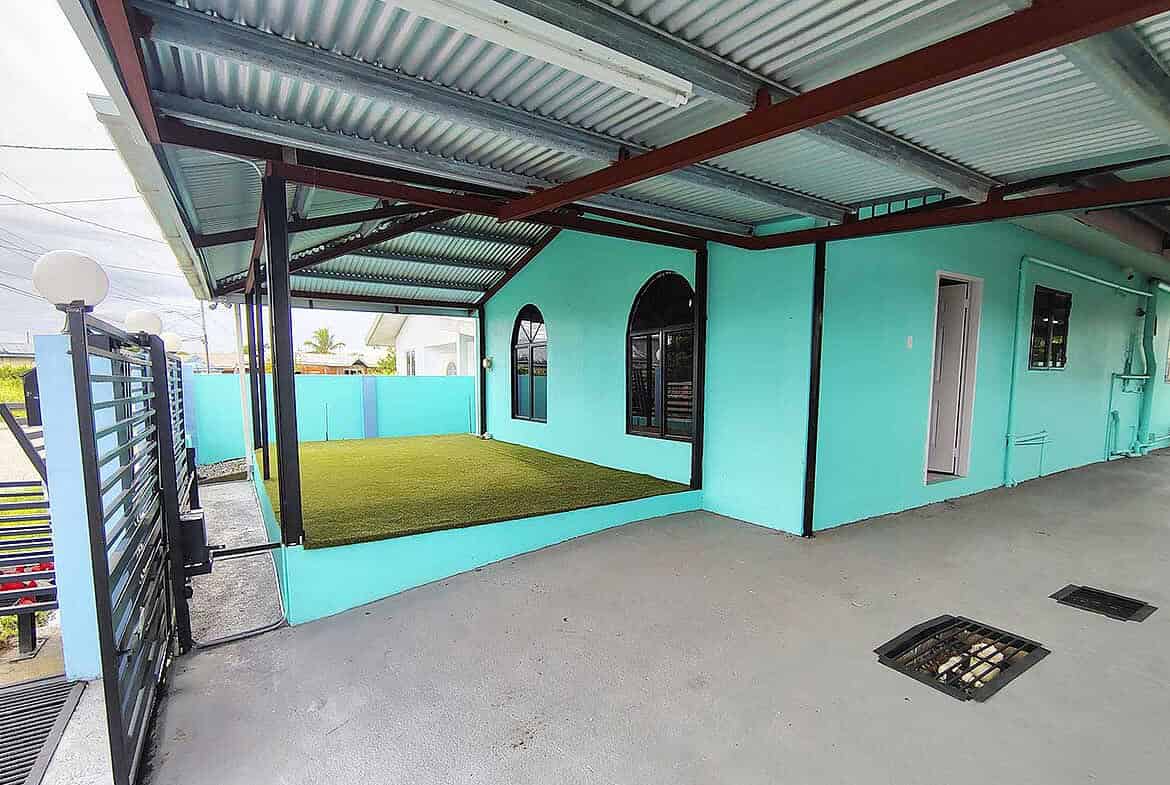 Cornerstone- Colorful turquoise building with a covered patio and artificial grass area in Edinburgh.