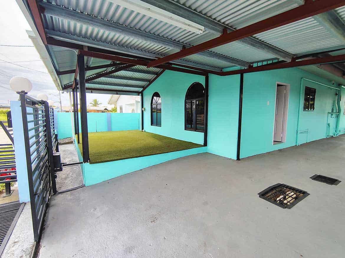 Cornerstone™ at Cashew Gardens, Edinburgh Cornerstone- Colorful turquoise building with a covered patio and artificial grass area in Edinburgh.