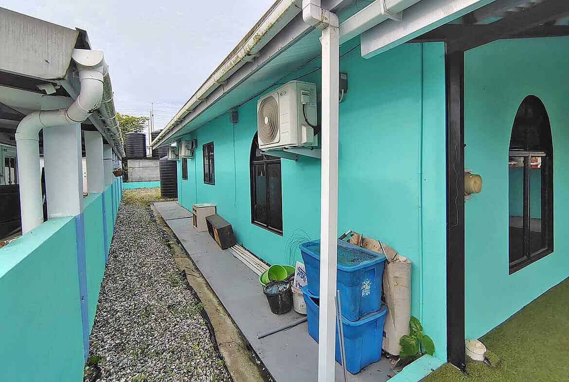 Cornerstone- Colorful turquoise building with air conditioning and outdoor storage at Cashew Gardens.