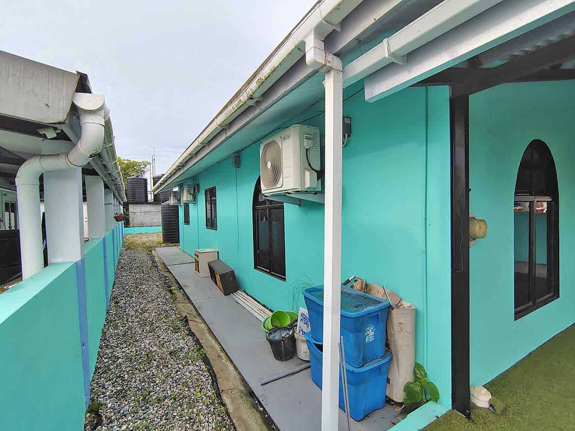 Cornerstone™ Building at Cashew Gardens Cornerstone- Colorful turquoise building with air conditioning and outdoor storage at Cashew Gardens.