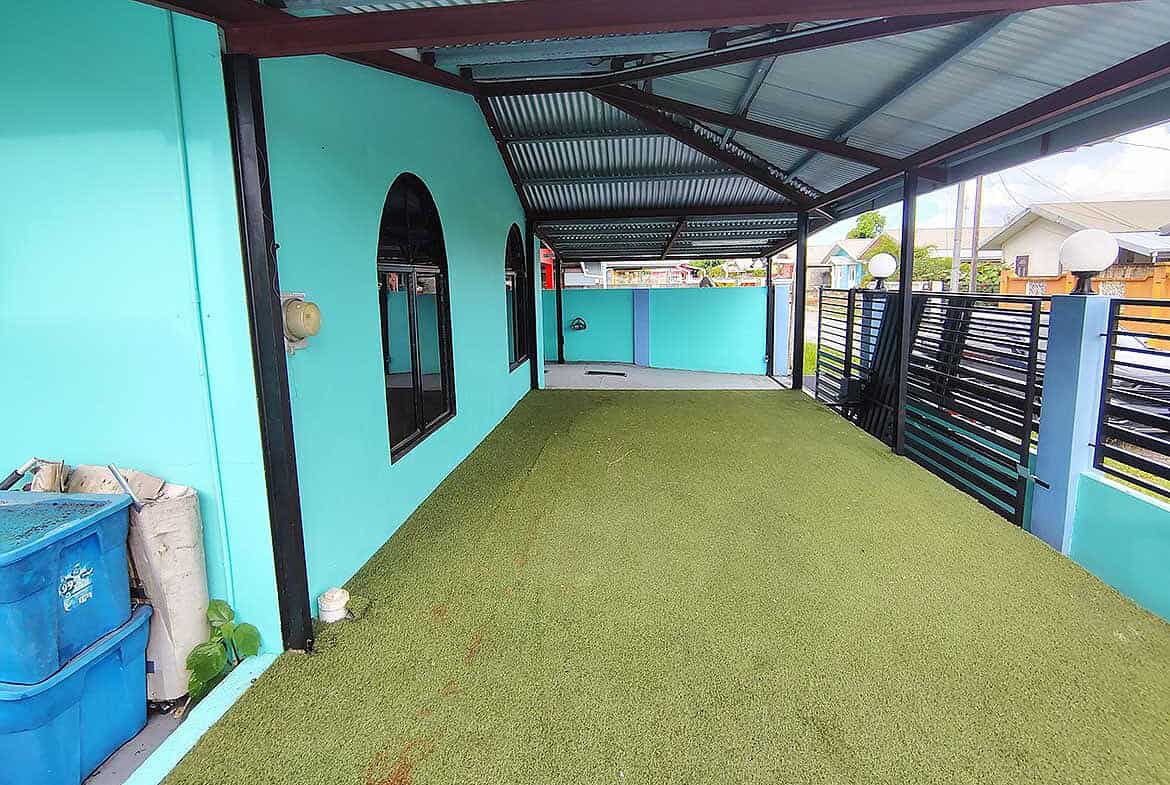 Cornerstone- Bright turquoise building with black window frames and green artificial grass.