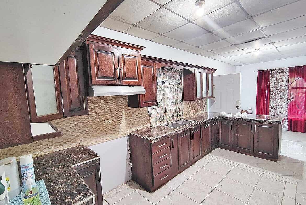 Cornerstone- Spacious kitchen with wooden cabinets and tiled floor in Cashew Gardens, Edinburgh.