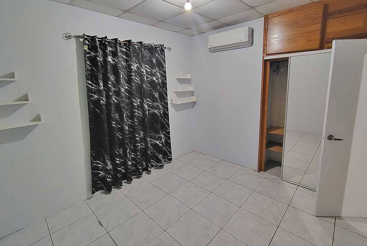 Cornerstone- Empty room with black curtains, air conditioner, and closet at Cashew Gardens.